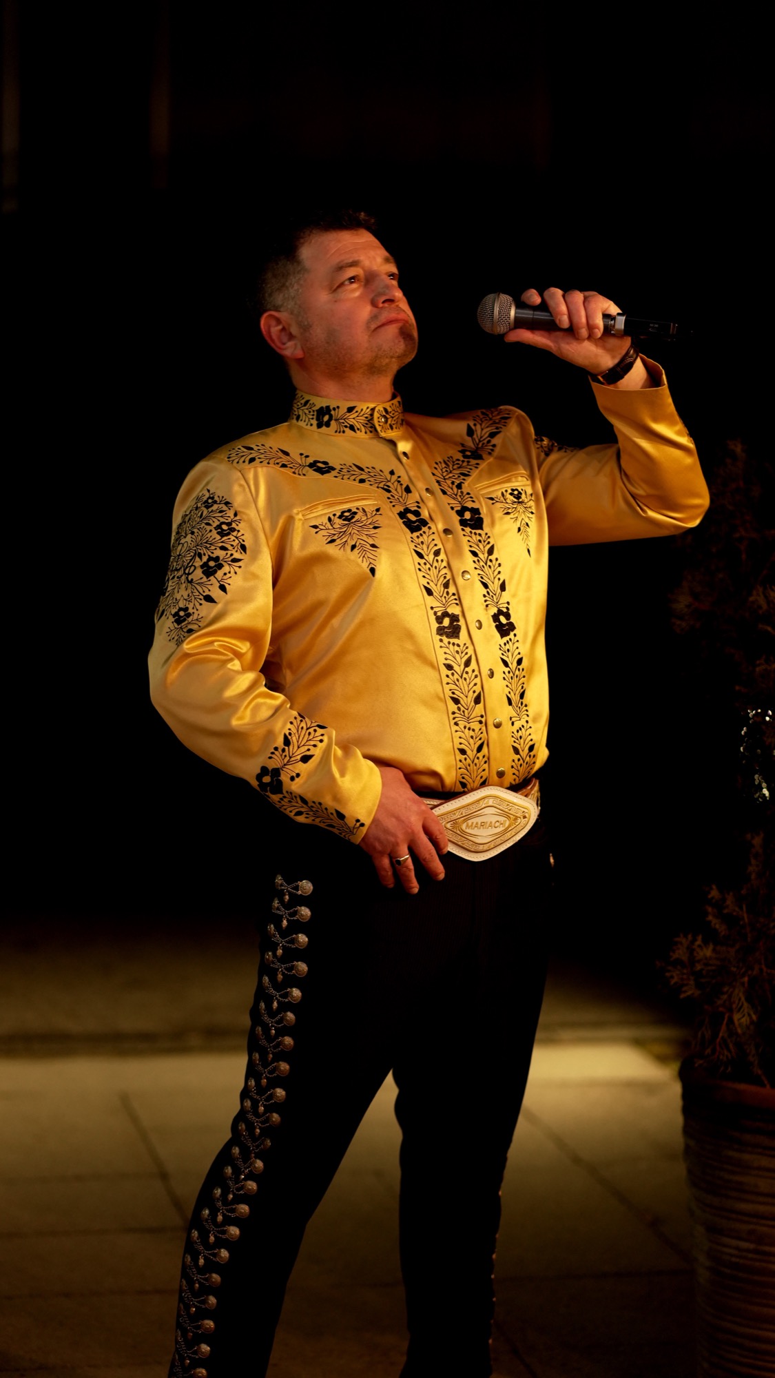 Luis Antonio Núñez con micrófono y traje de mariachi dorado